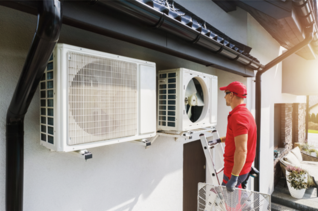 HVAC Technician on Ladder Installing Heat Pump on Outside Wall of Home