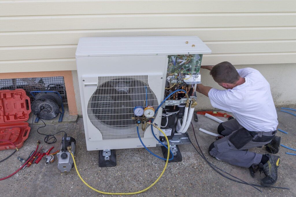 Person doing heat pump maintenance outside of a house