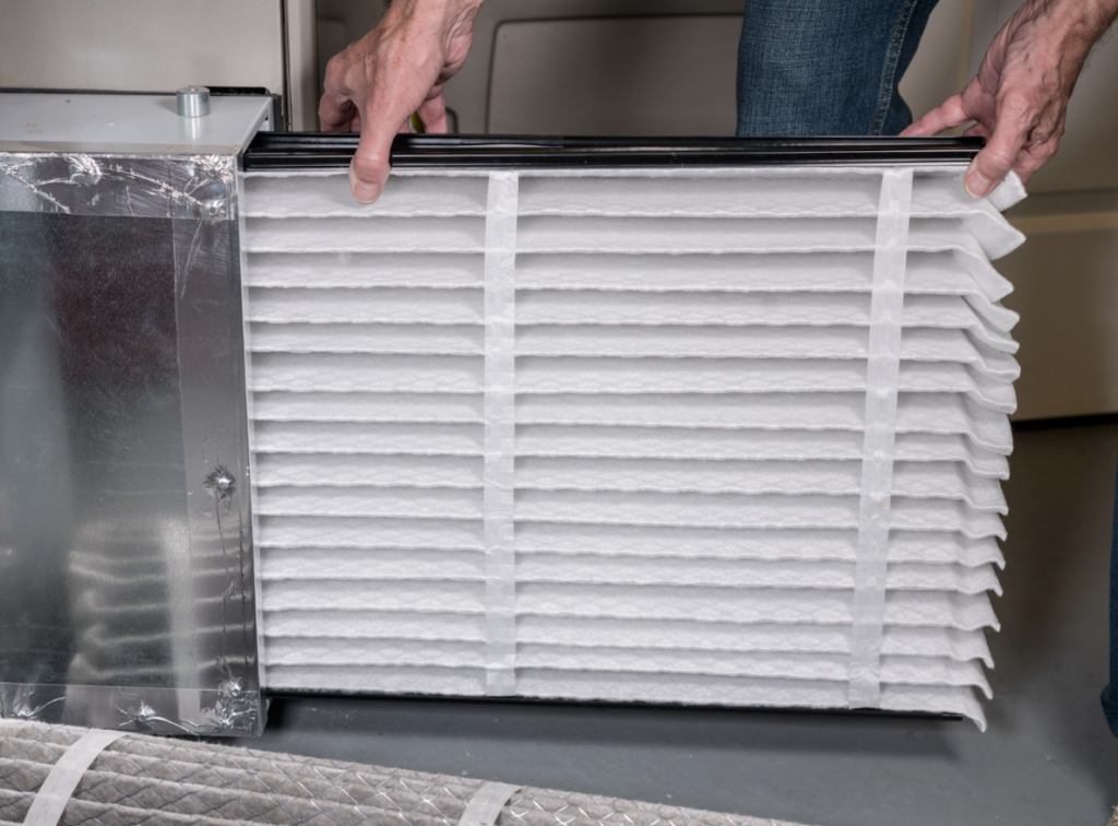man inserting clean air filter into home ac unit