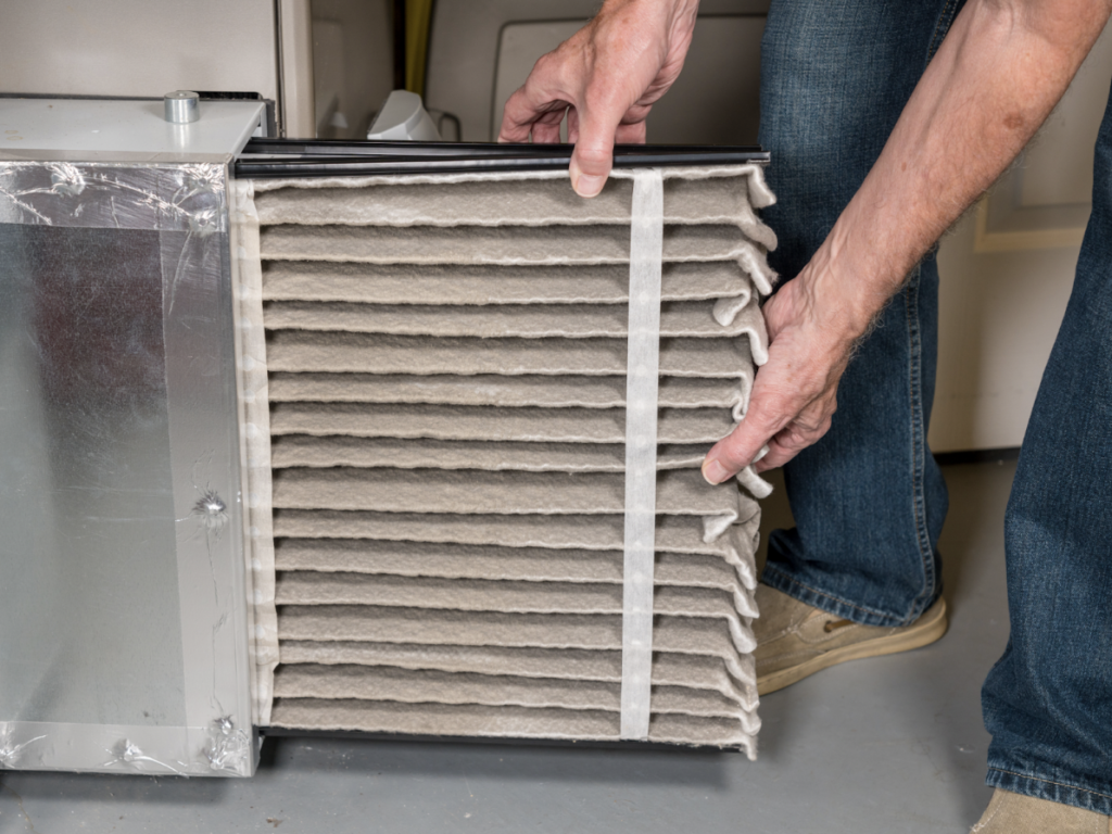 man removing dirty air filter frome home ac unit