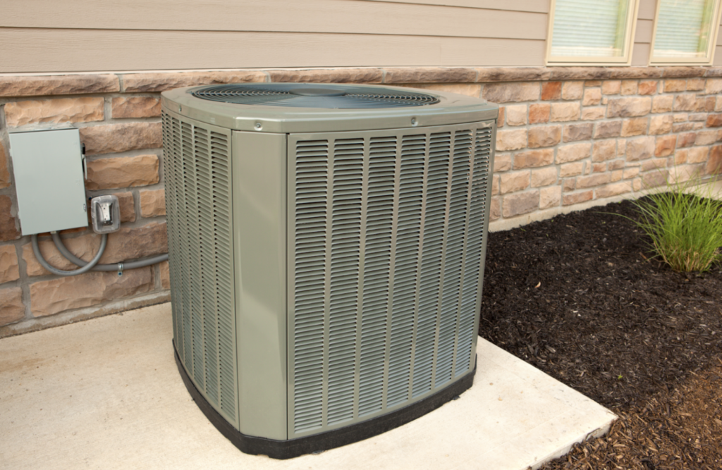 outdoor air conditioning unit on concrete against brick wall of house